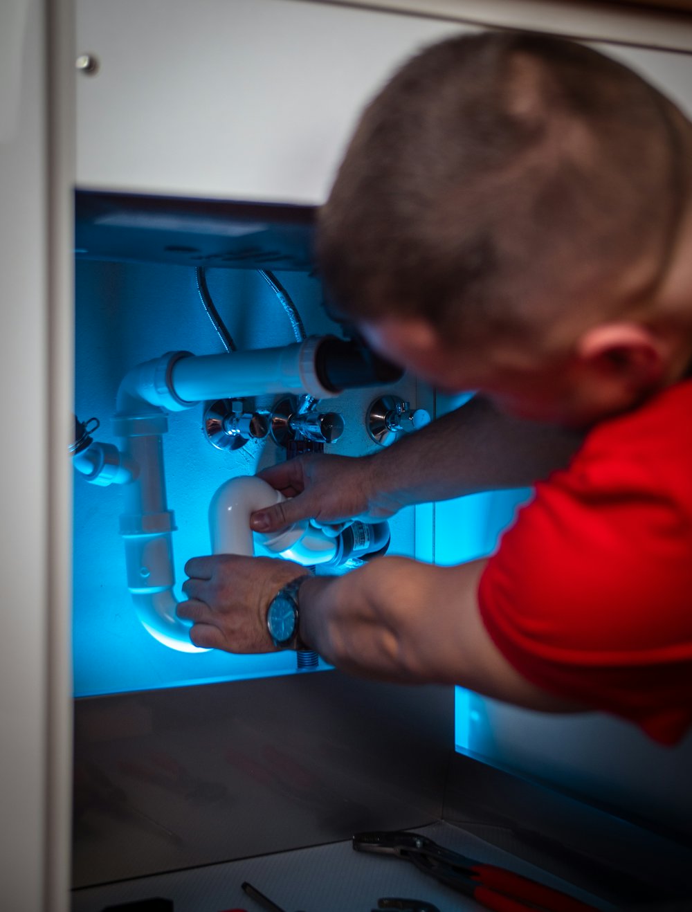 Plumber repairing pipes under a sink
